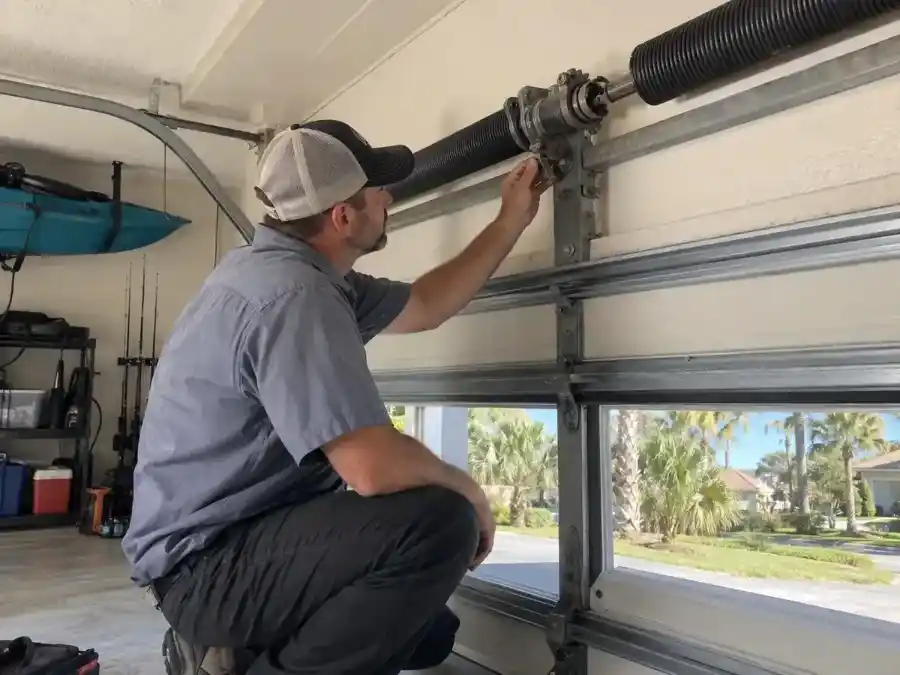 Palm Coast Garage Door Co. technician inspecting a broken torsion spring on a residential garage door in Flagler County, Florida offering Emergency Garage Door Repair Palm Coast